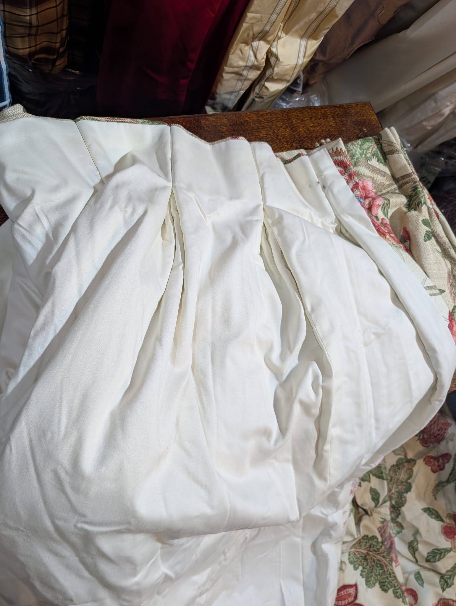 Close-up of crumpled white bedsheets with a floral-patterned quilt edge on the right side.